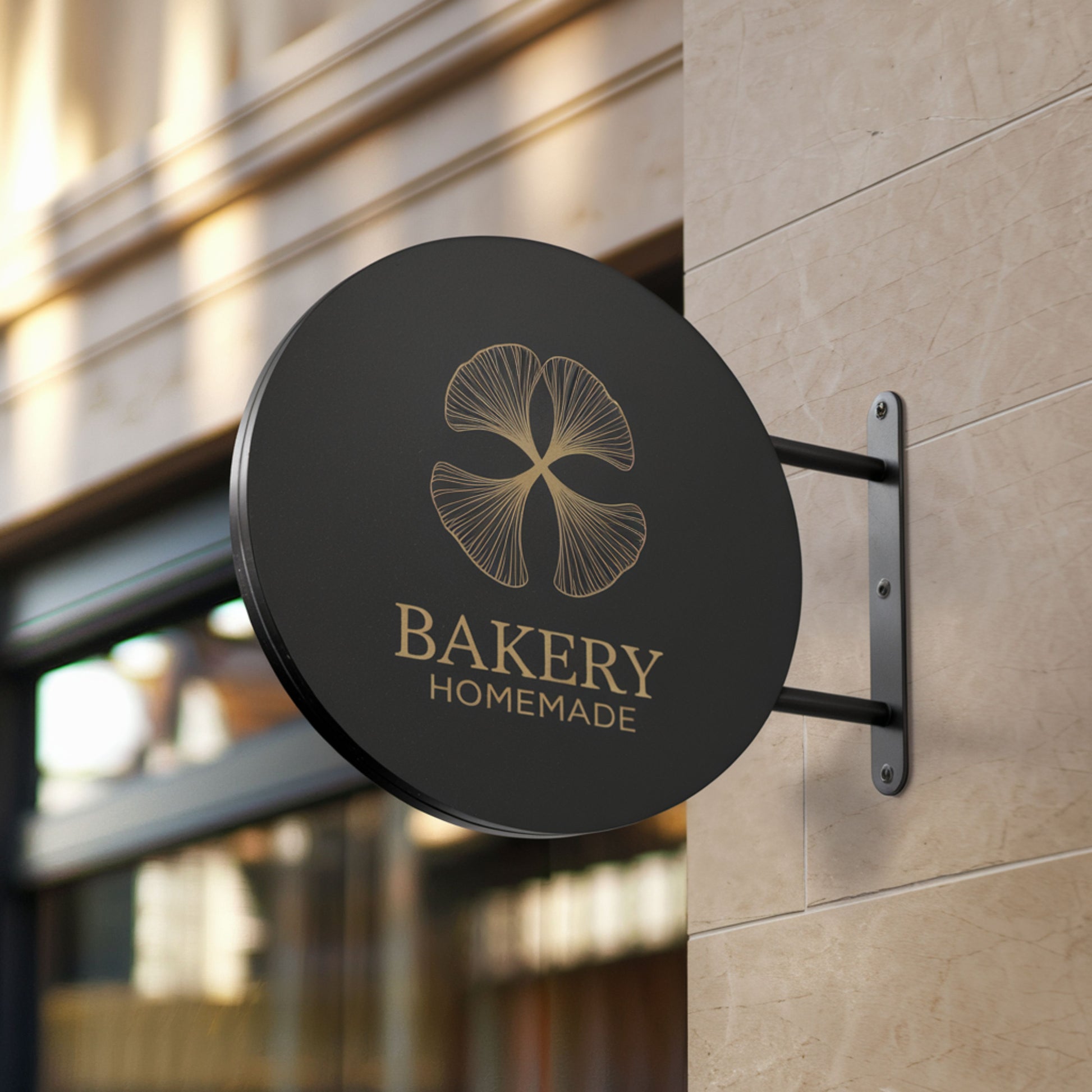 Round black bakery sign with gold logo and text on a building exterior